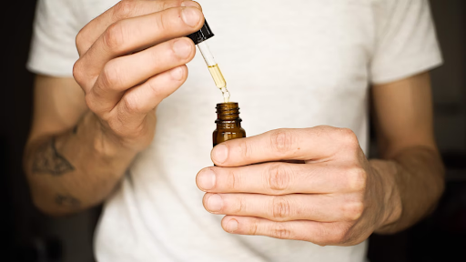 a guy in a white shirt showing an oil product for beard